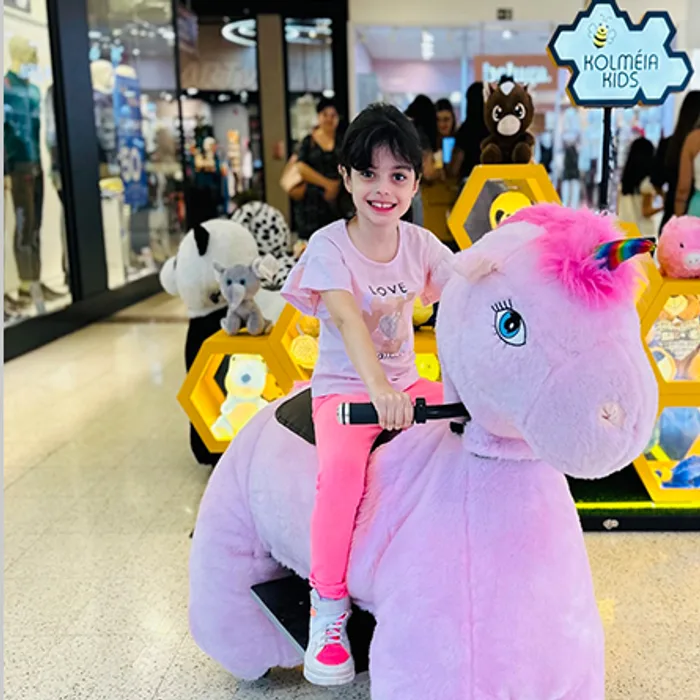 Menina passeando no unicórnio motorizado